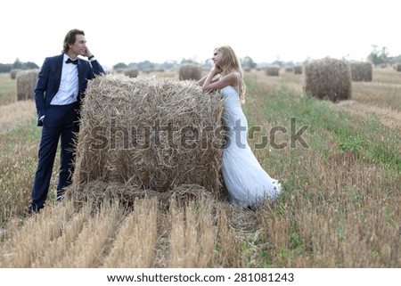 Married couple staring one another deeply in love, on a hay bale.