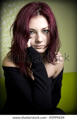 Sad red haired girl looking up and scratching her face.
