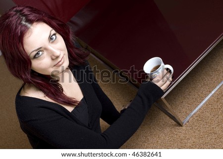 Lovely red haired woman relaxing on carpet while enjoying her morning tea.