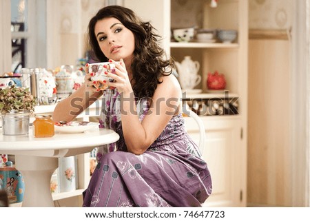 Lovely woman drinking her tea while is looking away. See more images from the same shoot.