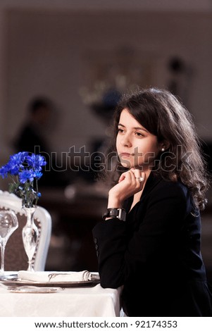 Lovely young woman thinking at someone when is having dinner in a romantic restaurant. Please see more images from the same shoot.