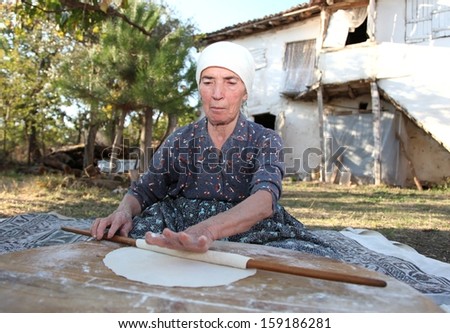 Old Anatolian (Turkish) woman is rolling out the paste