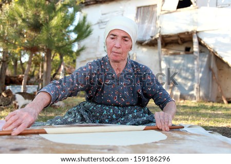 Old Anatolian (Turkish) woman is rolling out the paste