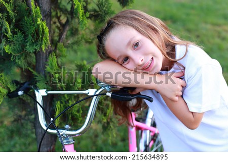 Photo of a young happy girl smiling while looking her new bike