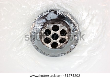 Basin drain with running water, stainless steel sink hole macro close-up