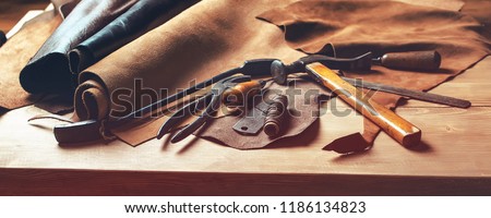 Shoemaker\'s work desk. Tools and leather at cobbler workplace. Set of leather craft tools on wooden background. Shoes maker tools on wooden table