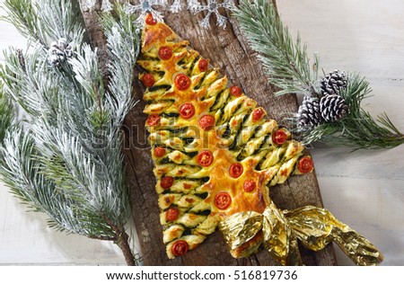 Christmas Tree of puff pastry on to a wooden board. fir branches around