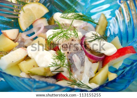 herring salad with apple , potato gherkin ,dill and sour cream in blue glass bowl for christmas