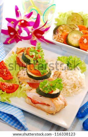 baked chicken breast filled with parma ham and cheese served with rice and zucchini-carrot salad