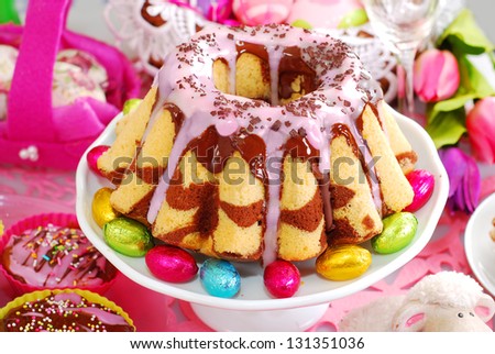 homemade marble ring cake poured chocolate sauce and pink icing on easter table