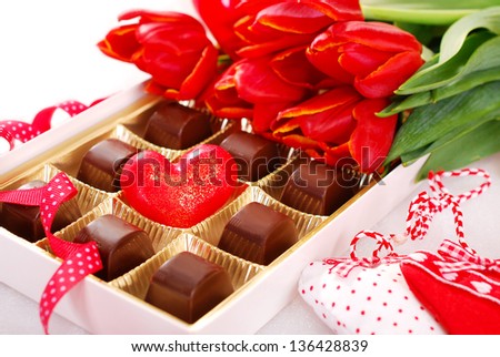 box of chocolates with red heart inside and bunch of tulips