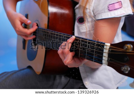 close up on the fingers of young girl playing acoustic guitar on the stage