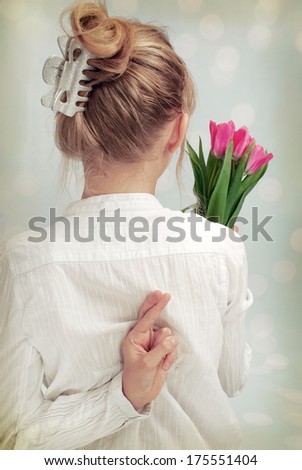 young girl holding bunch of tulips in one hand and second hiding on the back with crossed fingers (vintage style)