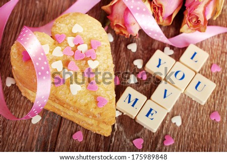 I love you made of scrabble letters ,dried roses  and heart shaped cookies with sprinkles  for valentine on wooden table