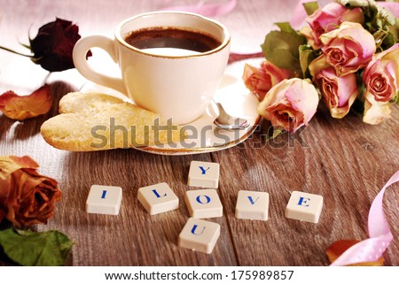 I love you made of scrabble letters ,dried roses ,cup of coffee and heart shaped cookies with sugar for valentine on wooden table