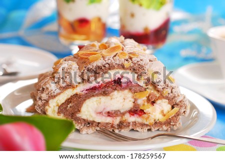 slice of meringue swiss roll cake with cherry cream and almond flakes