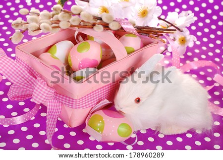 pink easter basket with eggs and white bunny on purple dotted background
