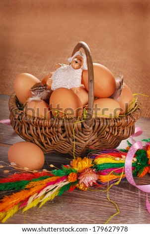 rural braided basket with fresh eggs and little sheep figurine on wooden table for easter