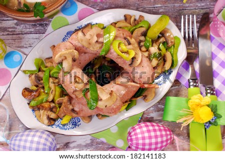 plate of white sausage fried with mushrooms and leek on old wooden table for easter dinner