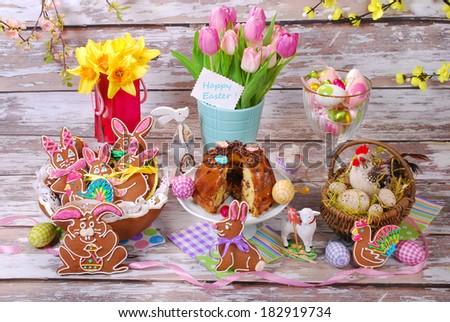 easter table decoration with handmade gingerbread cookies in basket and ring cake on old wooden background
