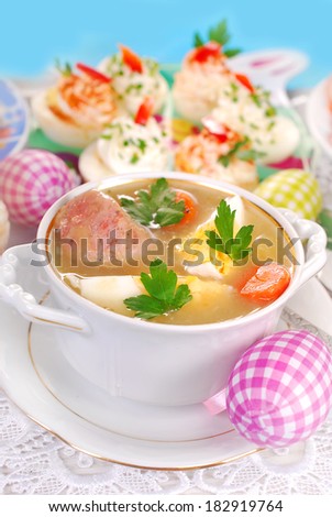 easter traditional white borscht (zurek) with egg ,sausage and vegetables in elegant dishware