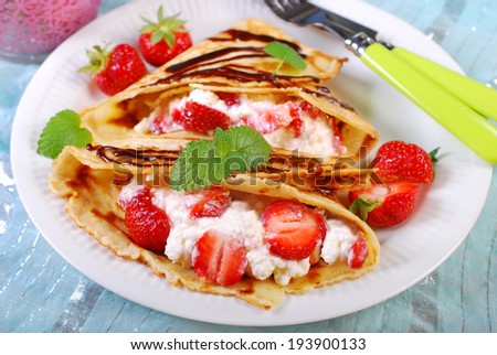 pancakes filled with cottage cheese,cream and fresh strawberries poured chocolate sauce