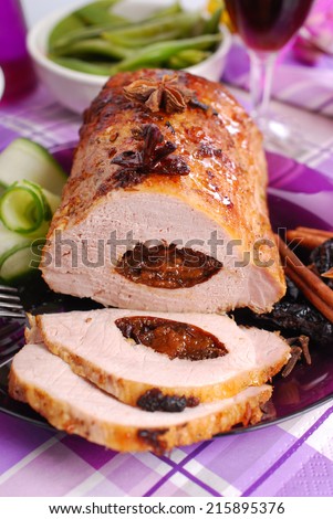 roasted pork loin stuffed with prune and spices on festive table