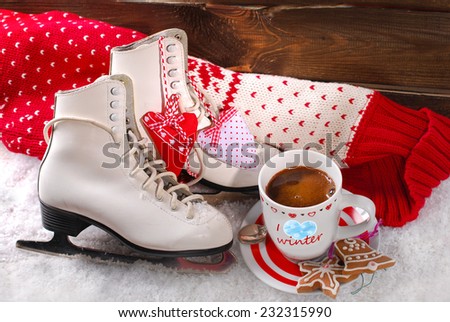 cup of coffee,pair of white ice skates and wool sweater on snow
