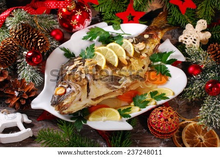 roasted whole carp stuffed with vegetables and almonds on wooden table for christmas