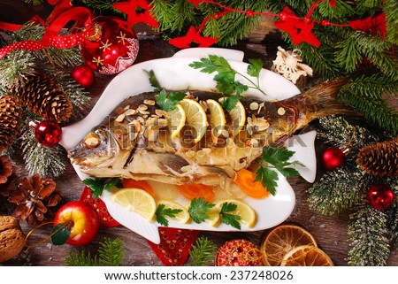 roasted whole carp stuffed with vegetables and almonds on wooden table for christmas-top view