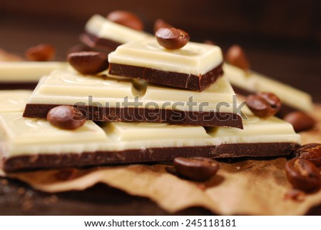 pieces of black and white coffee chocolate bar with seeds on wooden table