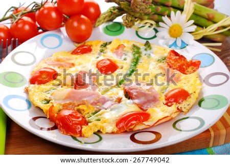 frittata omelet with green asparagus,cherry tomato and smoked ham on plate