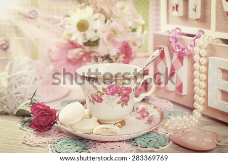 tea in fine china cup with roses ornament and anise meringue cookies in romantic vintage style