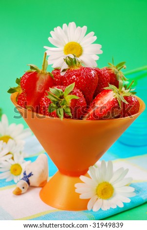 fresh strawberries in orange  bowl on green background