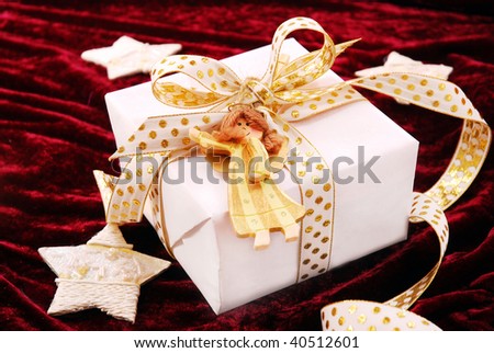 christmas present in white box with gold ribbon and wooden angel