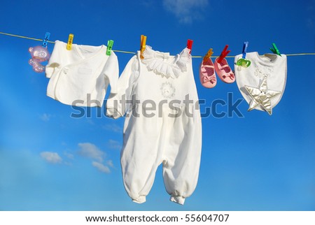 baby clothes and accessories hanging on clothesline against blue sky