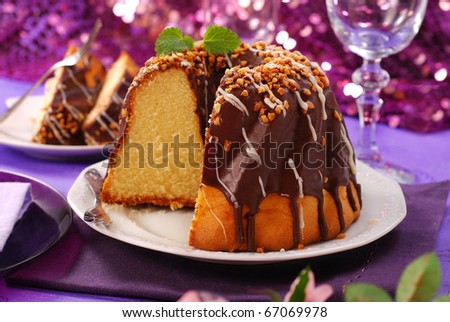 chocolate ring cake with nuts topping for party on purple shining background