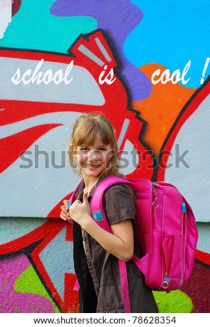 young schoolgirl with  pink backpack showing good luck sign