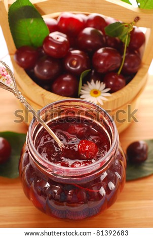 jar of homemade cherry confiture and basket with fresh fruits