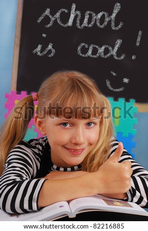 schoolgirl  sitting in the classroom showing good luck sign and \