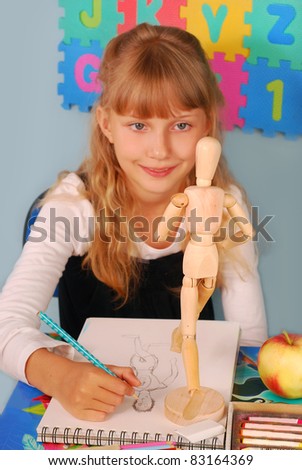 schoolgirl sitting in the classroom on drawing lesson with wooden model