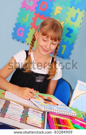 schoolgirl drawing a picture of dog with colored pencils sitting in the classroom