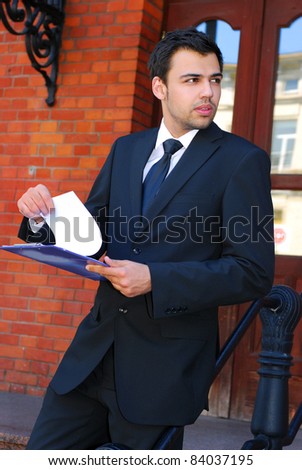 young businessman  standing in the front of bank building and checking documents