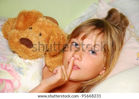 sleepy  young girl lying in bed with mascot asking to be silent