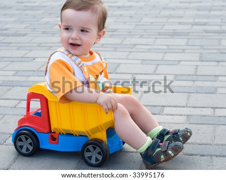 a smiling baby boy is sitting in the toy truck