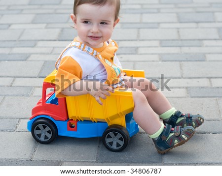 a smiling baby boy is sitting in the toy truck