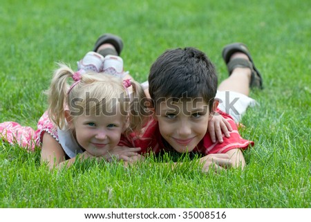 a little girl and a boy are lying on the grass in the park