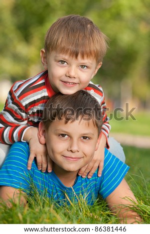 Two smiling brothers are playing on the grass