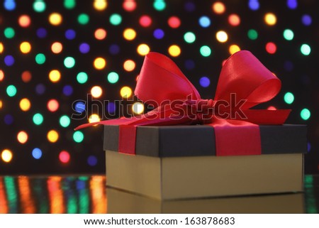 Gift box with a bow in front of a festive garland lights soft-focus background