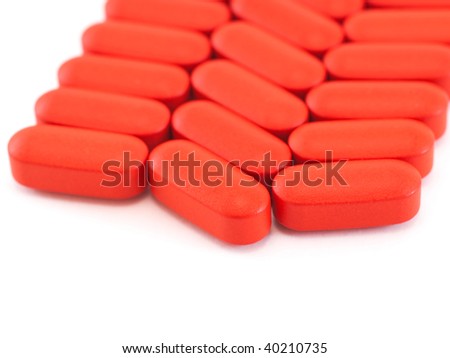 Red oval pills arranged in row on white background - stock photo